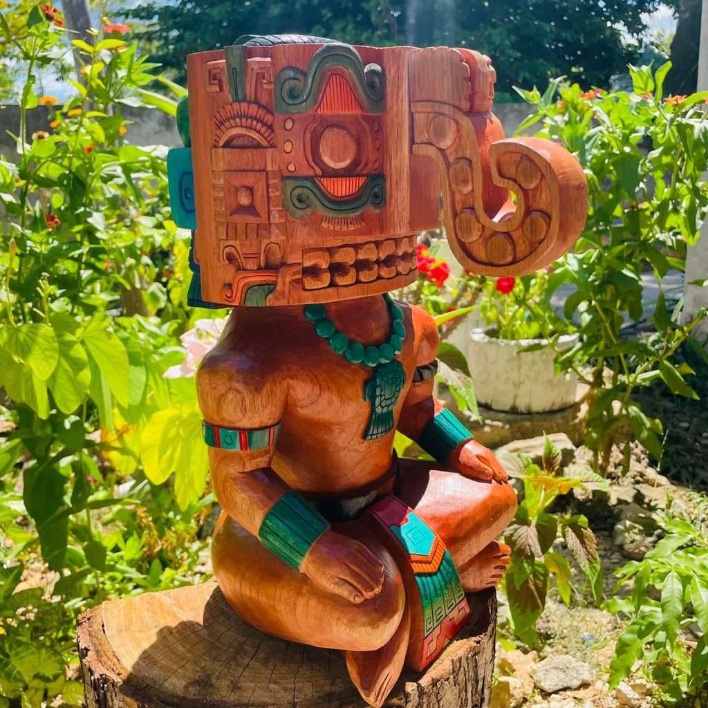 figura en madera del dios maya chaac de la lluvia sentado con adornos verdes de color jade